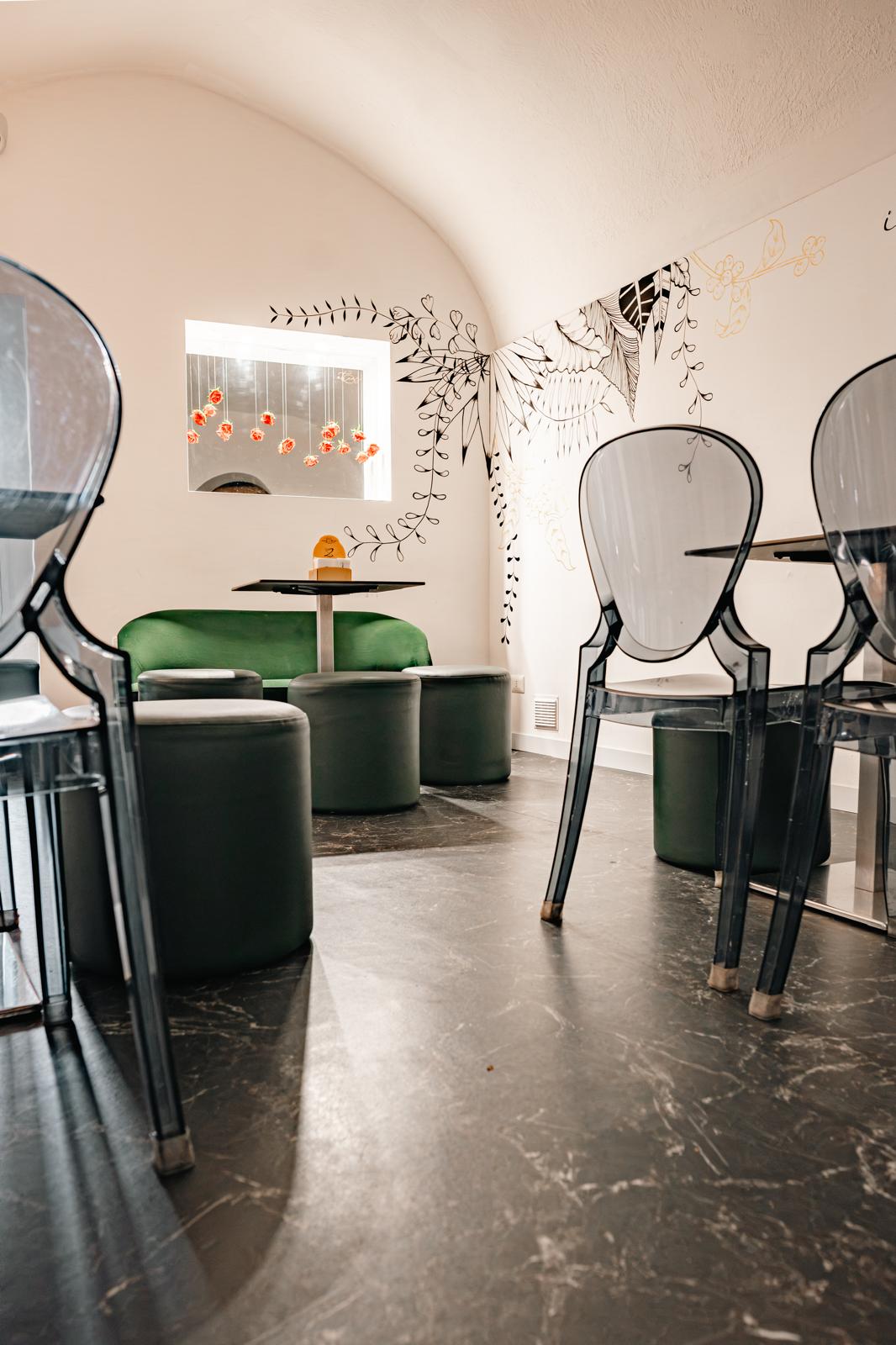 Sala interna con divano verde e sedie trasparenti